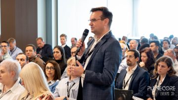 A delegate with a microphone asks a question from the audience at a previous PulseCore event