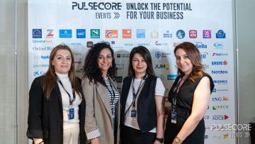 Four delegates pose in front of the PulseCore sponsor wall at a previous PulseCore event