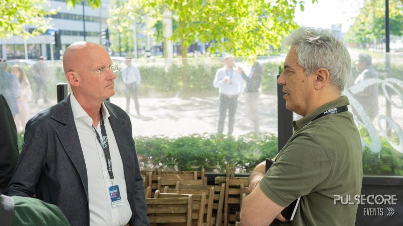 Two delegates in conversation by the venue windows at a previous PulseCore event